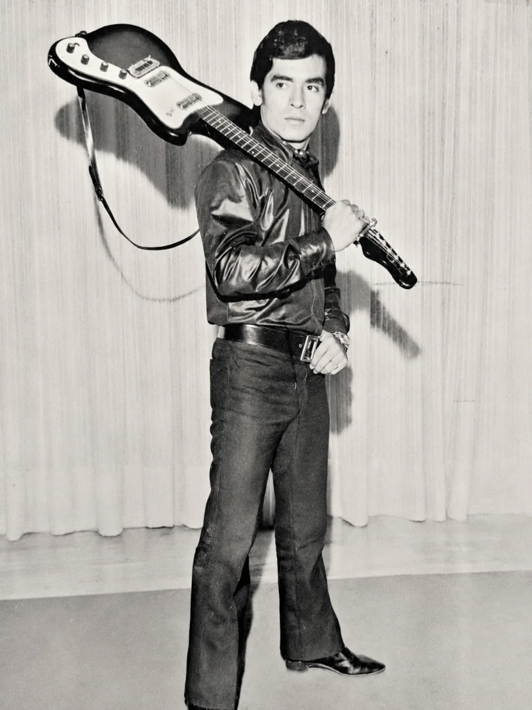 Retrato histórico en blanco y negro de Betulio Medina en sus comienzos, con una guitarra al hombro, durante la década de 1960.